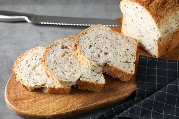 Freshly baked cut sourdough bread and knife on grey table, closeup