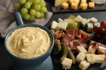 Fondue with tasty melted cheese and different snacks on table