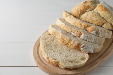 Freshly baked cut sourdough bread on white wooden table. Space for text