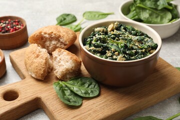 Tasty spinach dip with egg, bread and spices on grey table