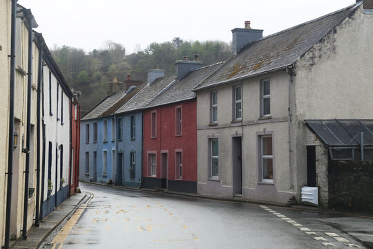 A row of painted terraced houses beside the very narrow main road through Fishguard, Pembrokeshire, Wales, UK.