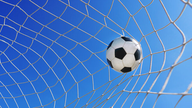 Fototapeta  Soccer ball in soccer goal net in a big stadium isolated on blue sky. soccer net.
