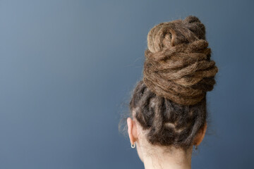 Minimal back view of unrecognizable Caucasian woman with dreadlocks in bun hairstyle copy space