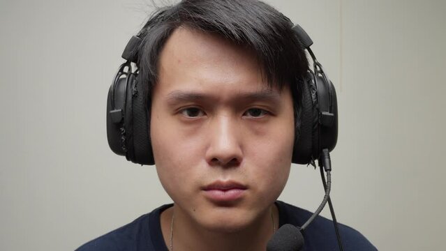 Music studio Chinese man producer puts headphones on and smiles listening waving shaking his head, closeup portrait face shot