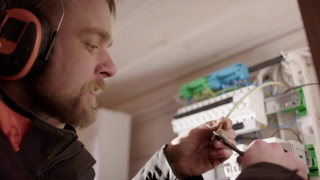 Electrician cutting and stripping distribution board wires. Close-up side view