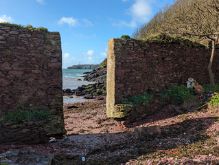 Monk Haven beach and the mouth of Milford Haven seen through a gap in an ancient wall at St....