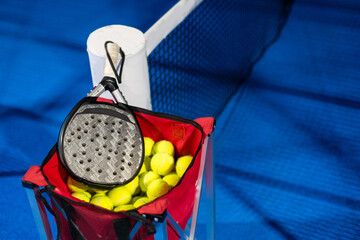 Black professional paddle tennis racket and ball with natural lighting on blue background. Horizontal sport theme poster, greeting cards, headers, website and app - obrazy, fototapety, plakaty