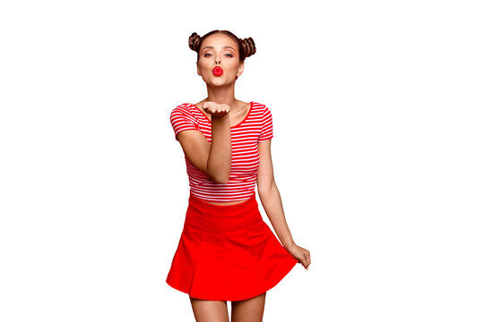 Cute girl send a kiss for you! Adorable young girl with nice make up wearing striped tshirt and red skirt isolated on bright background and sends air kiss from open palm