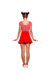 Full-legh full-size portrait of a young girl standing with her back to the camera on a bright red background