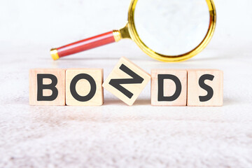 Bond indices on wooden cubes on an abstract background with a magnifying glass in the background