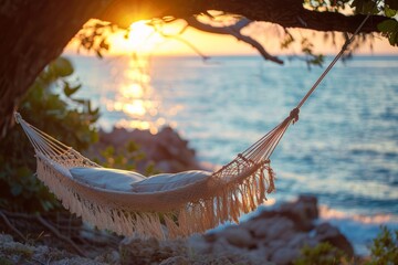 A hammock hanging from a tree over the ocean at sunset.