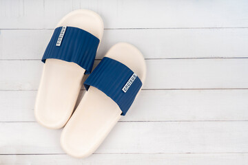 White and blue color rubber slipper shoes on wooden floor with copy space.