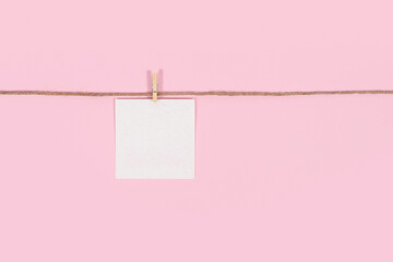 White paper cards on clothes-pegs on pink background