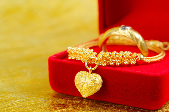 Gold ring on red velvet box on gold color.