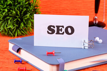 SEO Search Engine Optimization symbol on a white business card standing on a notepad