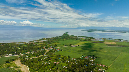 Island coastline with farmland and town. Negros, Philippines.