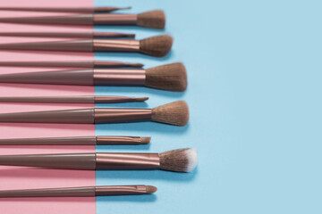 Naklejka premium Cosmetics and beauty. Make-up brushes set in row on blue background
