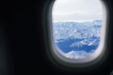Snowy Alp mountains view from a plane window - obrazy, fototapety, plakaty