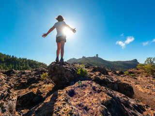 Obraz premium A woman hiker at a viewpoint of Roque Nublo in Gran Canaria, Canary Islands