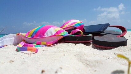 Closeup shot of a bikini and slippers on the sand in the Maldives