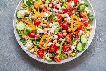 Healthy low carb salad with cauliflower rice, fresh vegetables, feta cheese and chickpeas