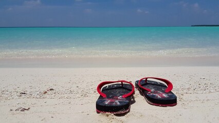 Closeup of a pair of flip-flops with the flag of Britain on a sandy beach