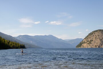 Fototapeta na wymiar Paddle boarder on a lake with mountains in the background