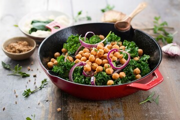 Sauteed kale with chickpeas and red onion - vegan dish in a cast iron skillet