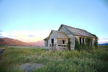 Old abandoned house in the middle of a meadow under a clrear sky