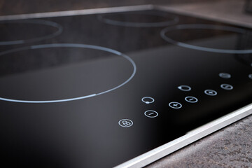 Modern induction electric hob cooker with control panel buttons. Electric hob detail closeup. Stove top panel controls of modern kitchen. Electric hob ceramic surface and touch control panel
