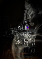 Closeup shot of a toy train with a locomotive steam engine against a dark background