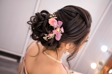Closeup shot of a woman's hairstyle ornamented with pink flowers