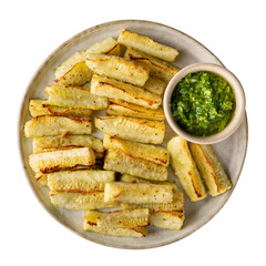 Oven baked zucchini wedges served with green pesto. Vegetable chips on plate isolated on white  background.