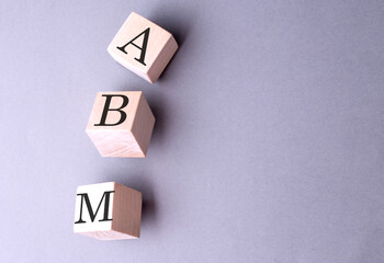 ABM word on wooden block on gray background