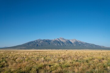 Landscape of hills covered in greenery under the sunlight and a blue sky