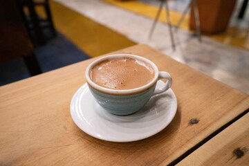 Delicious hot chocolate with milk at a restaurant in a small mug with a plate under it