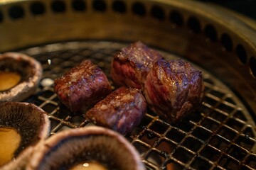 Cooked mushrooms and slices of wagyu steak on an Asian hot pot grill at restaurant