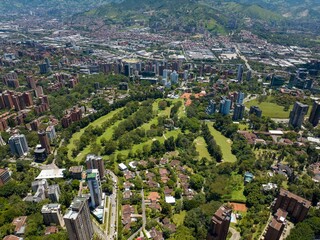 Aerial shot of a downtown El Poblado in Medellin, Colombia with green-covered hills on background
