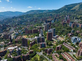 Aerial shot of a downtown El Poblado in Medellin, Colombia with green-covered hills on background