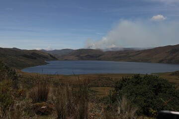 Scenic view of a lake surrounded by hills under a cloudy blue sky