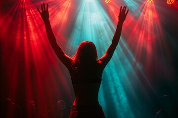 a woman in front of colored lights on stage with hands raised up