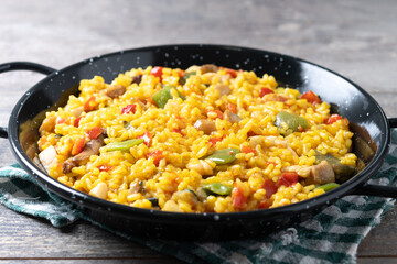 Yellow rice with chicken and vegetables on wooden table