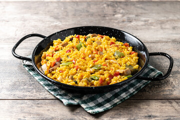 Yellow rice with chicken and vegetables on wooden table