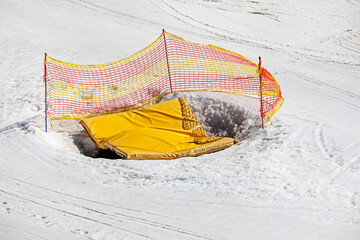 earthen pit covered with a yellow mat fenced with a net on a snowy slope, Safety and Active recreation with the family