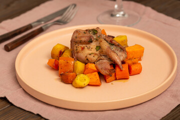 A portion of baked root vegetables, sweet potatoes, carrots, white, yellow, orange, blue with quail
