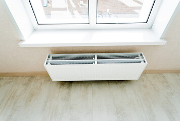 Top view of the radiator under the window in a private house, white radiator of the heating system.