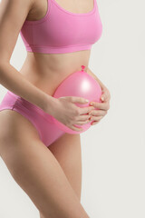 Young woman holding balloon as a sign of an stomach inflation, bloating and menstrual cramps...