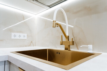 A golden sink in the kitchen in a private house, a design solution for the kitchen area in an...