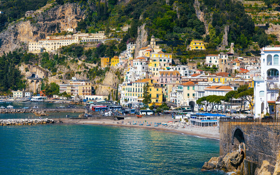 Amalfi on hills leading down to coast, comfortable beach and azure sea in Campania, Italy
