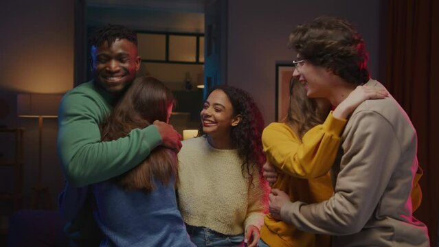 Positive company in colourful clothes hugging each other
